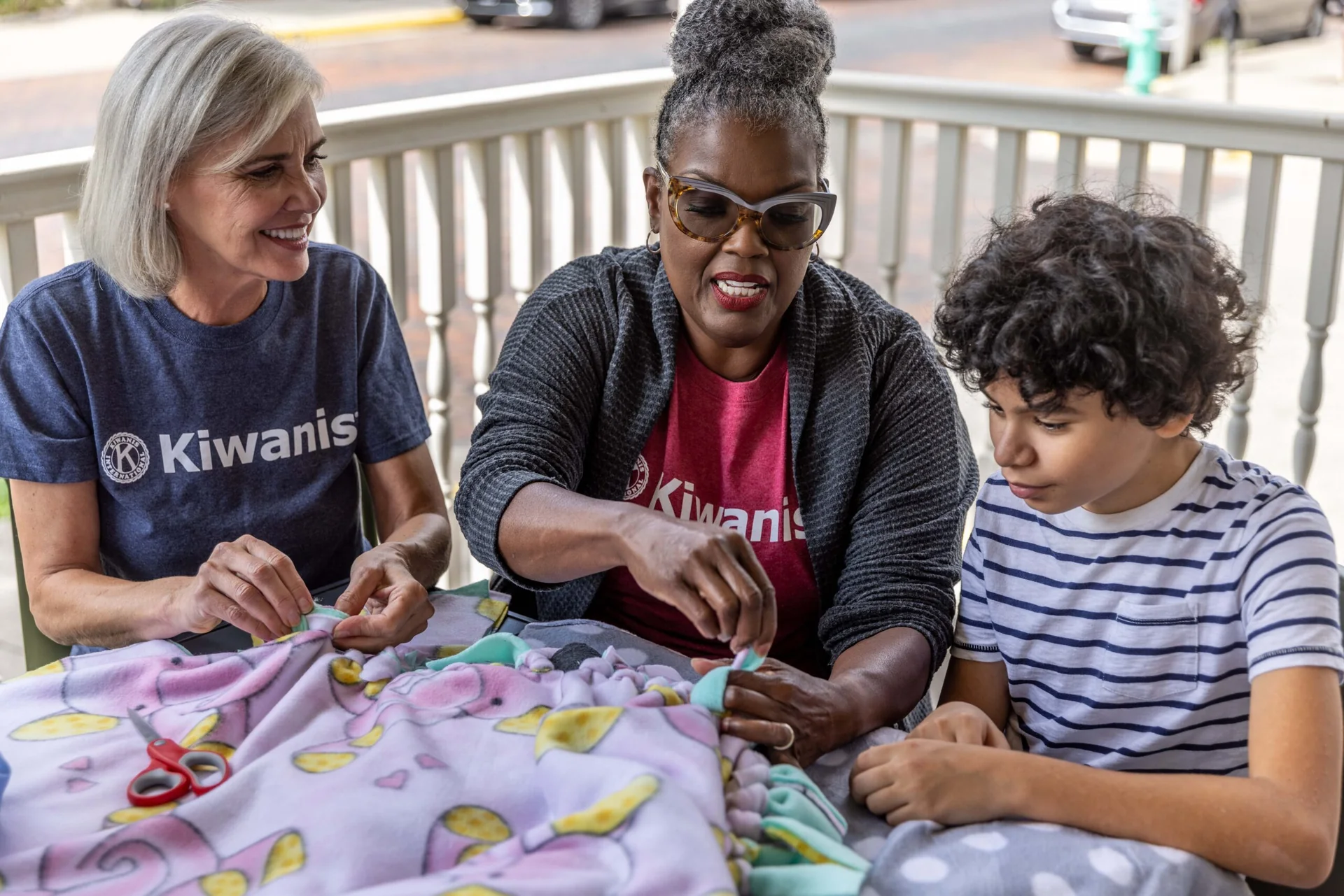 Denham Springs Kiwanis volunteers and a young person making blankets during a service project